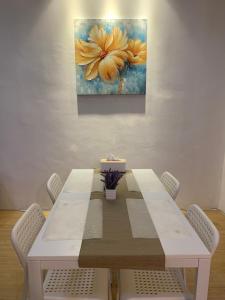 une table avec des chaises et une peinture de fleurs dans l'établissement Full House Ville Rawang, à Rawang