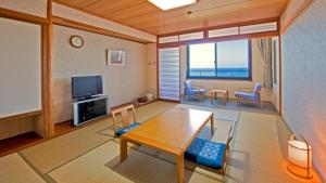 un soggiorno con tavolo, sedie e TV di Kyukamura Tateyama a Tateyama