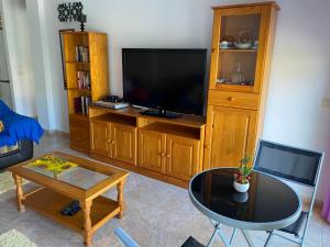 Una sala de estar con un televisor de pantalla plana y una mesa. en Heliocentro II -JÚPITER EN EDIFICIO REMEDIOS, en Los Llanos de Aridane