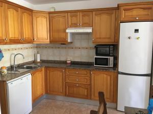 Una cocina con gabinetes de madera y un refrigerador blanco. en Heliocentro II -JÚPITER EN EDIFICIO REMEDIOS, en Los Llanos de Aridane