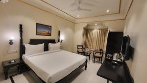 a bedroom with a bed and a television and a table at The Grand Barso (A Luxury Heritage) in Bharatpur