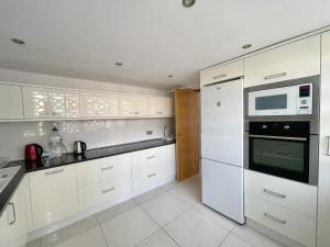 a white kitchen with white cabinets and a microwave at Torre Colon in Benidorm