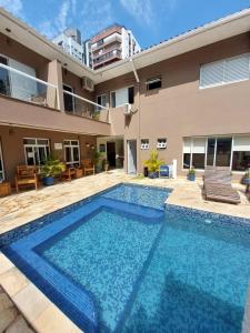 a swimming pool in front of a house at Hotel Casarão Pitangueiras in Guarujá