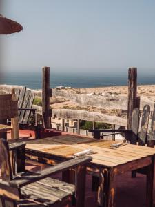 a wooden table and chairs with the ocean in the background at WaveGo Surf Camp in Imsouane