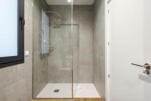 baño con ducha y puerta de cristal en Feelathome Castilla Apartments, en Madrid