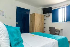 a bedroom with a bed and a desk and a blue door at Casa Flor Hostel & Drinks in Ríohacha
