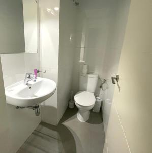 a white bathroom with a toilet and a sink at Ritual Sevilla Suites - Malaver 23 in Seville