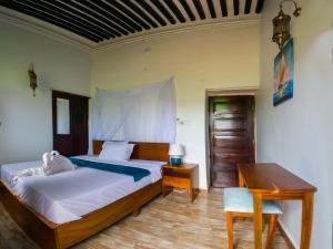 a bedroom with a bed and a table and a desk at Aurelia Zanzibar in Ngambo
