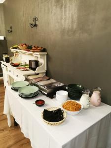 una mesa blanca con platos y tazones de comida. en Hotel Kārklu Muiža en Jelgava