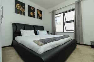 una camera da letto con un letto grande con testiera nera di The Quintessential getaway a Midrand