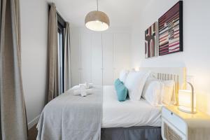 a bedroom with a bed with white sheets and blue pillows at Feelathome Castilla Apartments in Madrid