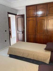 a bedroom with a large bed with wooden cabinets at Villa a tamaris dar bouazza in Casablanca