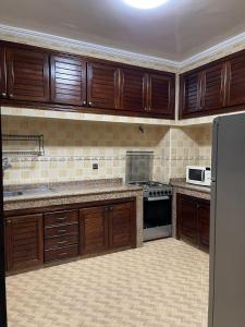 a large kitchen with wooden cabinets and a refrigerator at Villa a tamaris dar bouazza in Casablanca