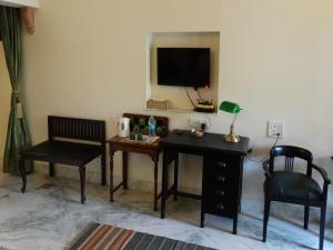 a room with a desk and a tv on the wall at Badnor House - The Heritage Homestay in Ajmer