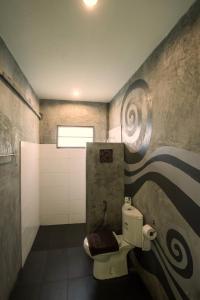 a bathroom with a toilet and a painting on the wall at River CoCo @ Amphawa in Samut Songkhram