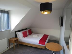 Un dormitorio con una cama con almohadas rojas y una mesa. en Eazy apartments, en Newcastle