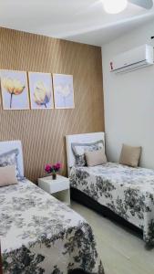 two beds in a room with flowers on the wall at Apartamento no Farol da Barra. Vista deslumbrante para o mar! No circuito do Carnaval. Ao lado do Porto da Barra ! in Salvador