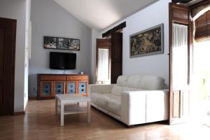 uma sala de estar com um sofá branco e uma televisão em Vivienda Turística Yamaries em Úbeda
