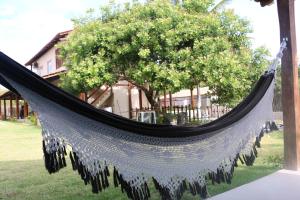 a hammock in front of a tree with a house at Flats Corumbau in Corumbau