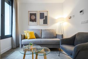 - un salon avec un canapé et une table en verre dans l'établissement Feelathome Castilla Apartments, à Madrid