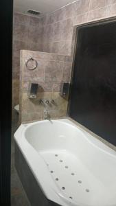 eine weiße Badewanne im Bad mit einer Kachelwand in der Unterkunft HOTEL PARQUE en Merlo- Buenos Aires in Merlo