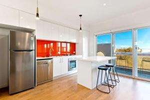 a kitchen with a refrigerator and a counter with stools at 2Bdrm Beachside Town House with Ocean Views in Seaford