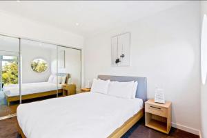 Un dormitorio blanco con una cama grande y una ventana en 2Bdrm Beachside Town House with Ocean Views, en Seaford
