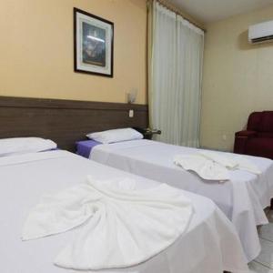 a hotel room with two beds with white sheets at Augustu's Hotel in Altamira