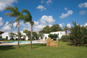 a palm tree in the grass next to a swimming pool at Tenuta Badessa in Casalabate