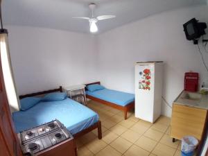 a small room with two beds and a refrigerator at Pousada Tuiuti in Tramandaí