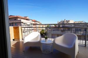 Un balcón con 2 sillas blancas y una mesa. en Piano Alto Home, en Pescara
