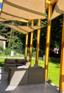 une pergola avec des canapés et des chaises sur une terrasse dans l'établissement Aranygesztenye Apartmanház, à Balatonudvari