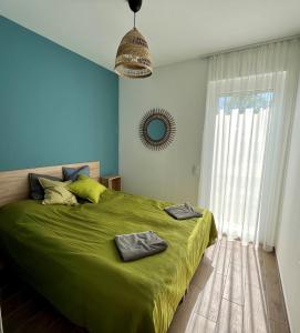 Un dormitorio con una cama verde y una ventana en Aranygesztenye Apartmanház, en Balatonudvari