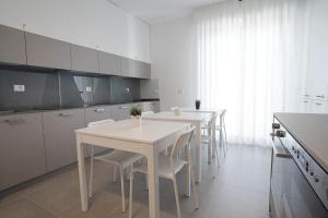 una cocina blanca con mesas y sillas blancas en Piano Alto Home en Pescara