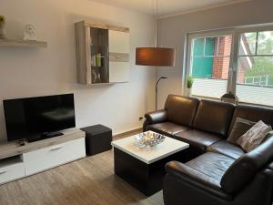 a living room with a leather couch and a flat screen tv at Ferienwohnung Landliebe in Leer