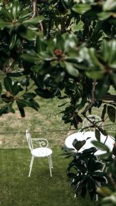 a white chair sitting in the grass next to a table at Puleera Boutique Hotel in San Leonardello