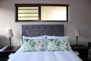 a bedroom with a bed with two pillows and a window at Amru Guesthouse B&B in Brackenfell