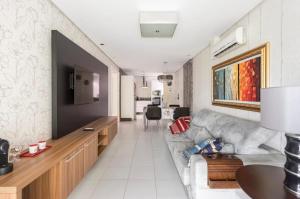 uma sala de estar com um sofá e uma televisão em Lindo Apto no Terraços da Rainha em Balneário Camboriú