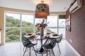 a dining room with a table and chairs and a large window at Lindo Apto no Terraços da Rainha in Balneário Camboriú