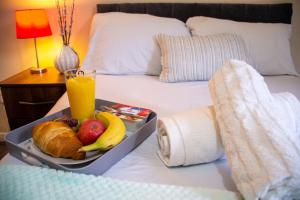 a tray of fruit and a drink on a bed at Royale Green View House- free parking, Wifi, Perfect for Contractors and Holiday in Northampton