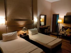 Pokój hotelowy z 2 łóżkami i lustrem w obiekcie The Exclusive House w mieście Peszawar