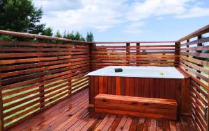 bañera de hidromasaje en una terraza de madera con una valla en Green Hills Forest Lodge en The Crags