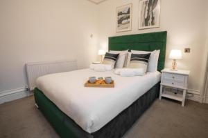a bedroom with a large bed with a green headboard at Milverton Hotel in Manchester