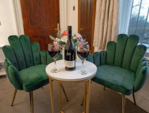 a table with two green chairs and a bottle of wine at Milverton Hotel in Manchester