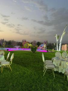 uma mesa e cadeiras num campo com um parque infantil em Jnane Nina em Tagadirt