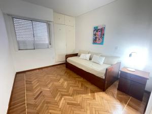1 dormitorio con 1 cama y suelo de madera en Departamento Parque Urquiza Amplio con estacionamiento en Paraná