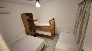 a small room with two beds and a chair at Casa Aconchegante in Maresias