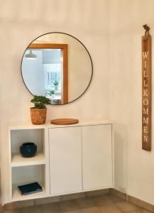 a mirror on a wall above a white cabinet at BOHO APARTMENT: NETFLIX + BALCONY + BATHTUB in Essen