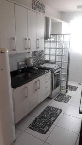 een keuken met witte kasten, een wastafel en een fornuis bij Condominio Recanto das palmeiras in Campos dos Goytacazes
