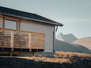 une maison avec une clôture en bois à côté d'une montagne dans l'établissement Camp Fjordbotn, à Galnslåtta